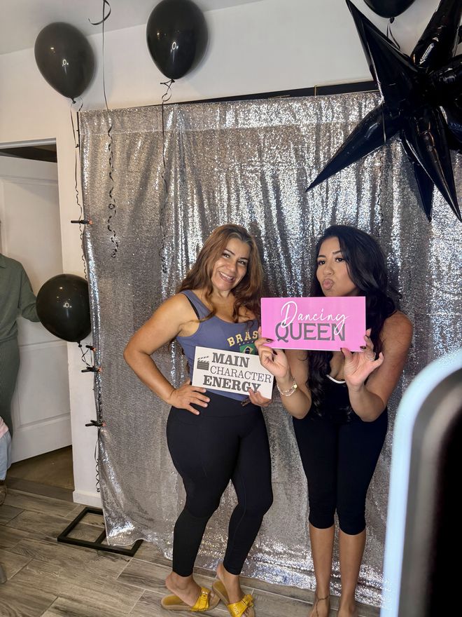 Two guests posing with Dancing Queen and Main Character Energy signs